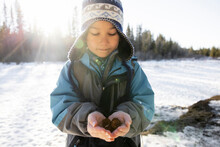 Portrait Of Boy Holding Fir Cones In Snow