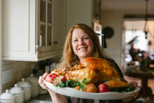 Smiling Grandmother Presenting A Cooked Turkey On Thanksgiving I