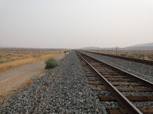 Endless Train Track In The Desert Against A Hazy Sky