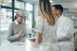 © Zamrznuti tonovi - Two pharmacist giving prescription medications to senior female customer in a pharmacy