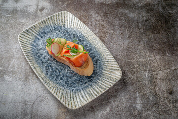 Sticker - Open sandwich with salmon, seabass, cucumber and radish on a gray stone table