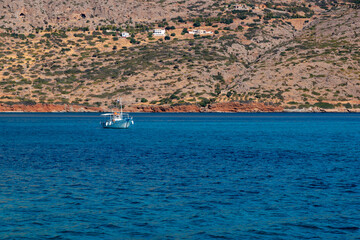 Sticker - Lonely boat in the sea peacefully floating by the coast of Crete island, Greece