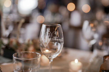 Wall Mural - Glasses and burning candles on the wedding table; blurry background bokeh lights