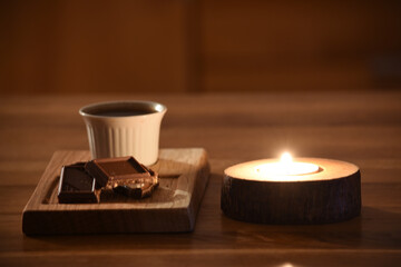 Poster - Candle and a coffee with chocolates on a wooden table