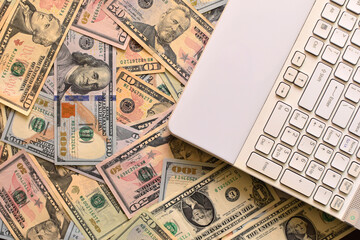 Wall Mural - Top view of a white calculator on dollars banknotes, the concept of earn money online