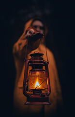 Wall Mural - Vertical shot of a young man in a yellow hoodie holding a lantern