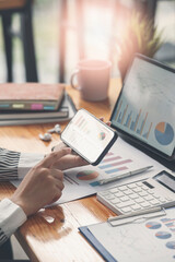 Businesswoman working at office with document on her desk, doing planning analyzing the financial report, business plan investment, finance analysis concept.Using smartphone and tablet.