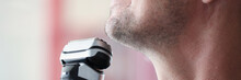 Young Man Shaves With Electric Razor Closeup