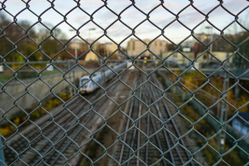 Poster - Closeup shot of a metal mesh with a train on the railroad in the background in Stockholm, Sweden