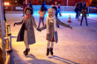 Beautiful gilfriends ice skating together; Winter joy concept