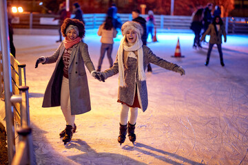 Wall Mural - Beautiful gilfriends ice skating together; Winter joy concept