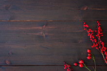 Winter Season And Christmas Background. Branches Of Dog Rose With Rose Hip And Red Barberry On Rustic Dark Brown Wooden Table. Flat Lay Template With Copy Space For Festive Table Top Designs.