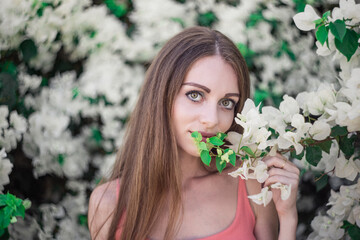 Wall Mural - Pretty Caucasian woman with long hair posing in the garden with many flowers in spring