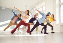 Group Of Happy, Positive, Cheerful, Smiling People Enjoying Contemporary Dance Class. Young Male And Female Dancers Wearing Trendy Glasses And Casual Wear Dancing Together In Light Modern Dance Hall