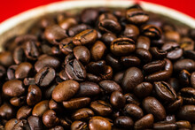 Closeup Roasted Coffee Beans In A Barrel Isolated On A Red Background
