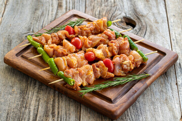 Wall Mural - Chicken skewers on a wooden background. Close-up of raw chicken skewers marinated in tomato sauce. Horizontal view