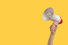 Megaphone In Woman Hands On A Yellow Background.