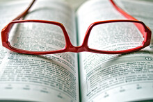 A Red Reading Glasses Lie On The English Dictionary