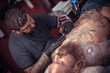 © Mr. Prof - Tattoo specialist showing process of making a tattoo in the salon