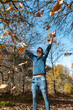 © magui RF - close up. young man plays with yellow leaves falling down. vertical composition