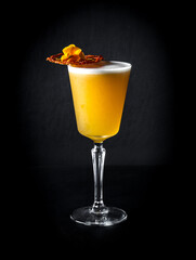 Poster - Vertical shot of orange cocktail in a glass with dried fruits isolated against a black background