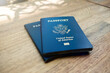Two blue American passports laying on a wooden desk