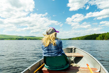 Woman On A Boat With Blonde Hair Blowing In The Wind. Woman On A Maine Lake In Old Aluminum Power Boat Enjoying Summer Vacation.