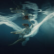 A girl in a white dress posing underwater on a dark background as if she were in zero gravity