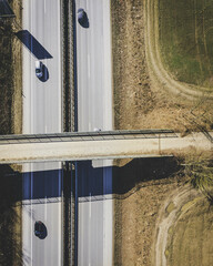 Poster - Aerial shot of two reciprocal roads and a bridge over it surrounded by a field