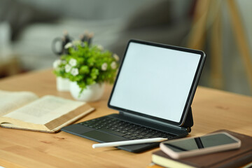 Poster - Photo of a white blank screen digital tablet on the wooden table surrounded by a stylus pen, notebook, smartphone, book and potted plant.