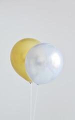 Silver and gold shiny balloons on plastic sticks against white background