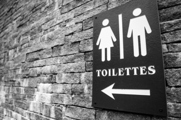 Canvas Print - Grayscale shot of a toilet arrow sign on a brick wall