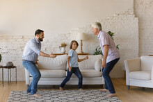 Overjoyed Young Father, Small Preteen Kid Boy And Middle Aged Mature Retired Grandpa Dancing To Energetic Disco Music Barefoot On Floor Carpet In Modern Living Room, Enjoying Entertaining Activity.