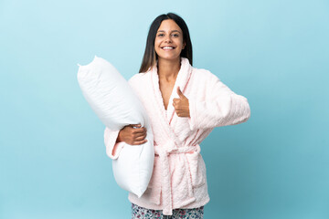 Young woman in pajamas over isolated background in pajamas and with thumbs up because something good has happened