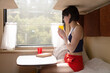 A woman sitting train compartment with a yellow mug of tea in her hands.