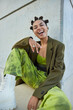 © WHstudio Leushin N - Vertical shot of overjoyed carefree teenage girl wears stylish green clothes laughs happily poses against concrete wall feels free spends free time outdoors. People fashion and style concept