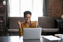 Happy Laughing Young African American Woman In Glasses Looking At Computer Screen, Clenching Fists Making Yes Gesture, Celebrating Getting Dream Job Offer Or Amazing Win News, Internet Success.