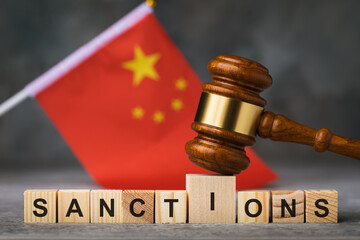 Wooden cubes with text and a judge gavel against the background of the Chinese flag, a concept on the theme of sanctions in China