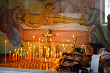 Memory Of The Dead. Candles On The Background Of Christ With A Crucifix And A Church Fresco Are Burning On The Memorial Candlestick In The Orthodox Church. Sacrificial Bread On The Table.