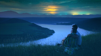 The man and woman sitting above the picturesque river