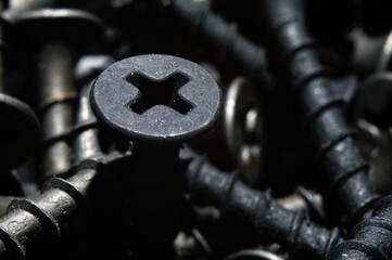 black hardened self-tapping screws lies on a dark background. close-up.