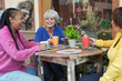 Elderly multiracial female friends enjoy coffee at bar outdoor