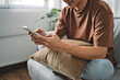 © mojo_cp - Young attractive man sitting on  sofa using smart phone at home.
