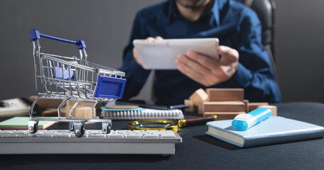 Wall Mural - Man using tablet computer. Shopping cart on the computer keyboard