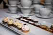 Babeczki i ciasteczka zaserwowane koło filiżanek przygotowanych do parzenia kawy i herbaty w restauracyjnej sali konferencyjnej.