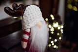 Fototapeta  - Ozdoba świąteczna, skrzat w ciepłej czapce, z białą brodą i porożem renifera. W tle światełka choinkowe