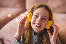 Een Girl In Modern Headphones Sit Relax On Floor Near Couch Listening To Music,