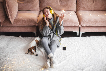 Wall Mural - teen girl in modern headphones sit relax on floor near couch listening to music