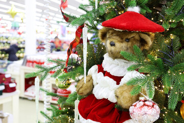 Wall Mural - Christmas tree with toy bear in a shopping mall. Festive decorations, store with gifts for New Year celebration