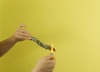 Wall Mural - Two hands lit a Bouquet garni. Smoke and fire on yellow background